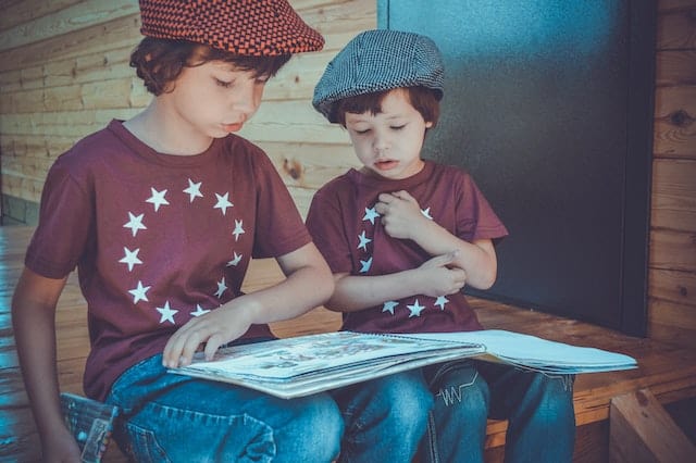 boys with hats reading large book