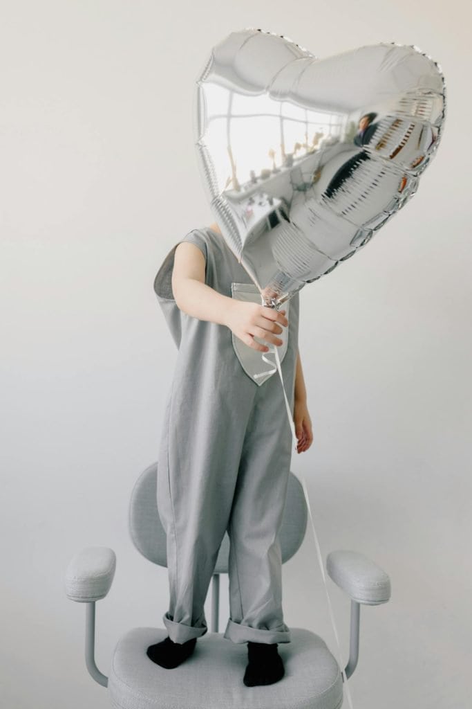 kid with silver balloon on chair